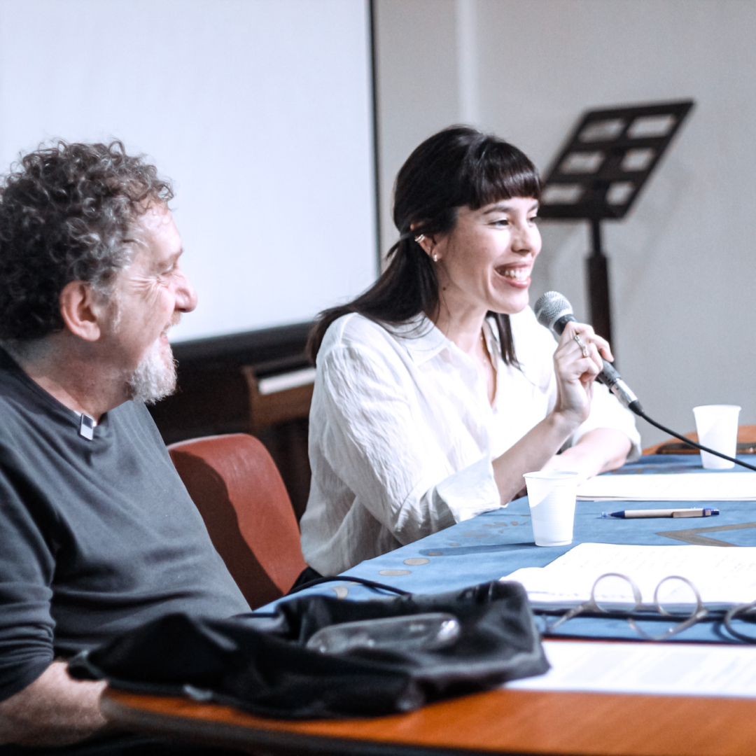 Tania com microfone apresentando a palestra de Carlos Skliar, sentado ao lado, antes de iniciar. UNIRIO